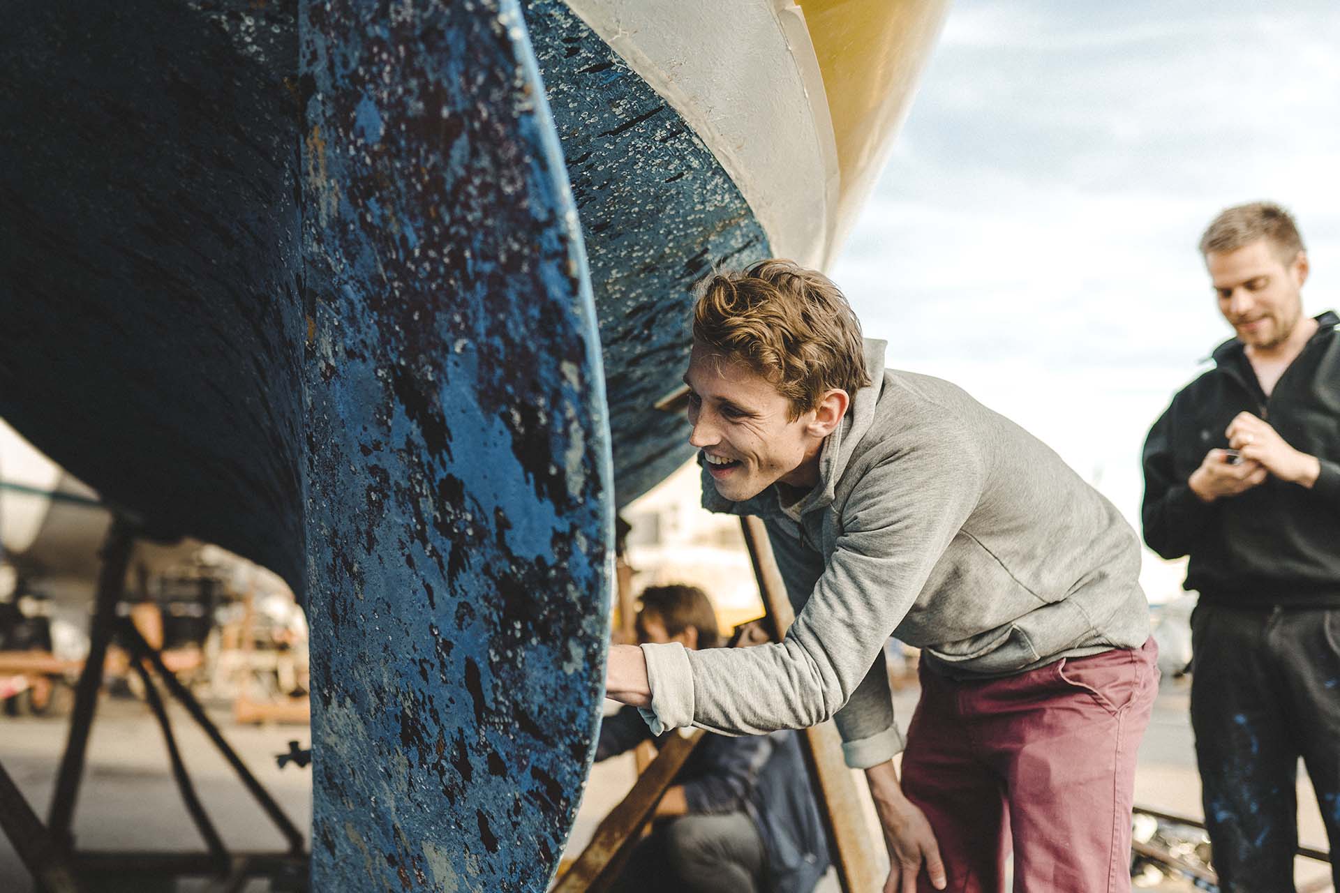 En leende man undersöker en segelbåt